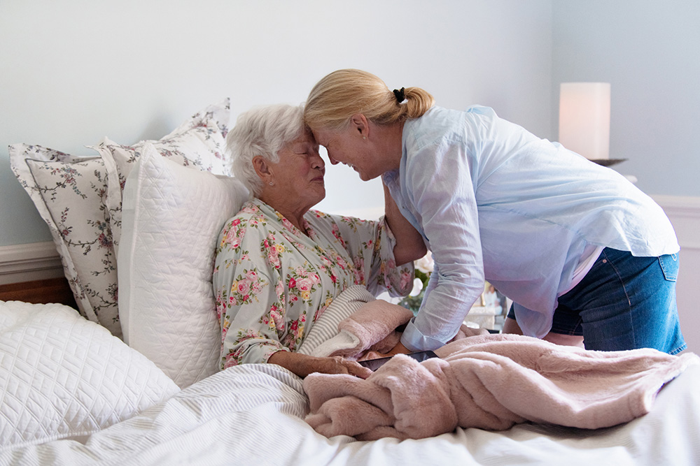 adult daughter resting her head against her senior mother's head
