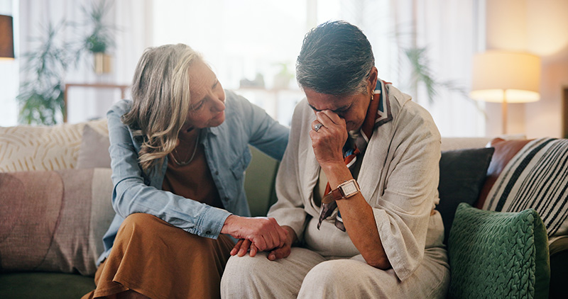 Woman, crying and holding hands in home with friends, support or compassion for healing from grief.