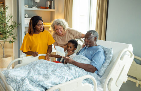 Patient in bed, reading book with family