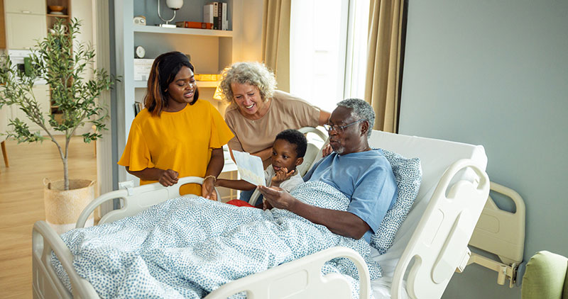 Patient in bed, reading book with family